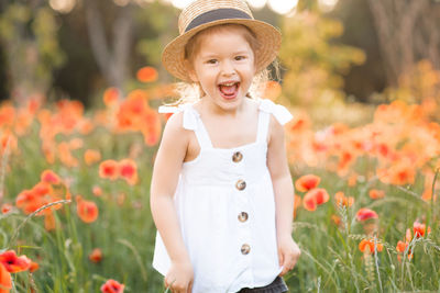 Portrait of cheerful girl wearing hat on flowering field