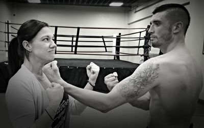 Couple gesturing while standing against boxing ring