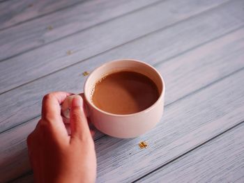 Cropped hand of woman holding coffee on table