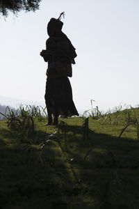 Rear view of man standing on field against clear sky