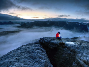 Nice woman sit on summit in hands hold lamp. girl wait in misty darkness for sun in high mountains