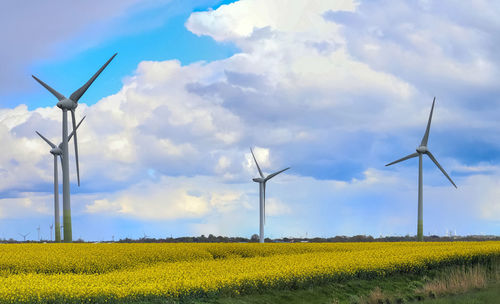 Wind turbines on field against sky