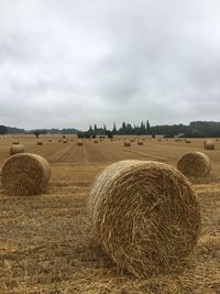 Hay bales on field against sky