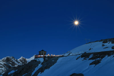 Low angle view of snowcapped mountain against blue sky