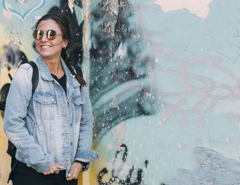 Urban portrait of a female standing in front of colorfully painted wall