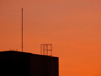 Low angle view of silhouette building against orange sky