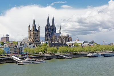 View of buildings by river against sky