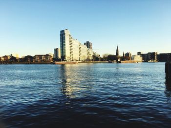 City at waterfront against clear sky