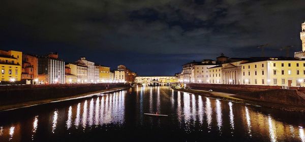 River by illuminated buildings against sky at night