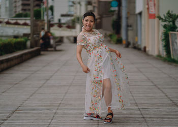 Portrait of woman standing on footpath