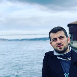 Portrait of young man standing against sea