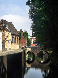 Arch bridge over canal amidst buildings against sky