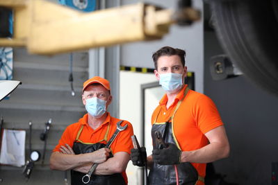 Portrait of coworkers wearing masks standing in workshop