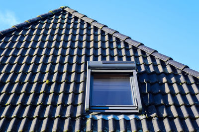 Roof window in velux style with black roof tiles