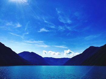 Scenic view of lake and mountains against blue sky