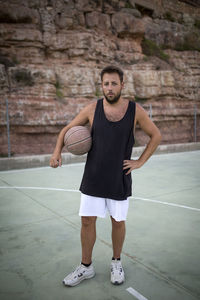 Full length portrait of young man standing against wall