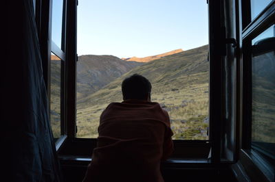 Rear view of man looking through window