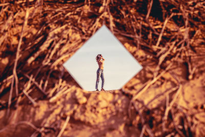 Reflection of woman in mirror standing against clear sky