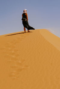 Low angle view of woman standing on sand dune