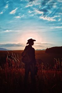 Man standing on field against sky during sunset