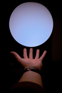 Midsection of woman holding illuminated lamp against black background