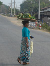 Rear view of woman with umbrella standing on road