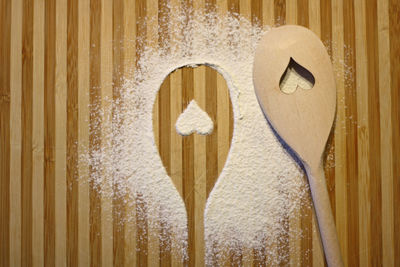 Close-up of heart shape in wooden spoon by flour on table