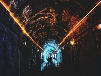 People walking in illuminated tunnel