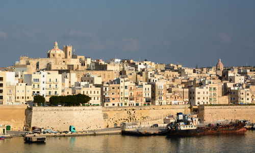 Boats in sea against buildings in city