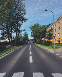 Empty road along trees and buildings