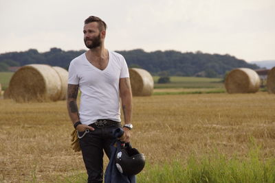 Young man with helmet standing on agricultural field