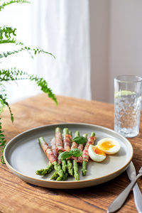Fresh asparagus wrapped in bacon and grilled, served with egg benedict. healthy food.