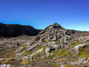 Low angle view of rocky mountains against clear blue sky