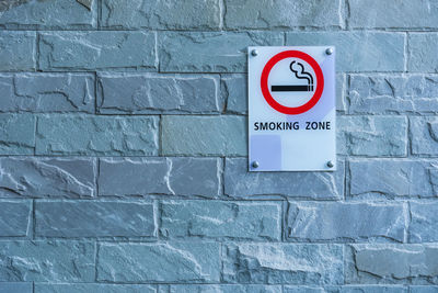 Close-up of smoking zone text on information sign against wall