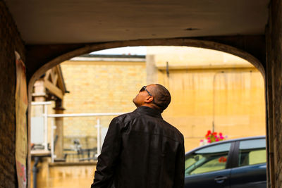 Rear view of man looking up while standing against arch