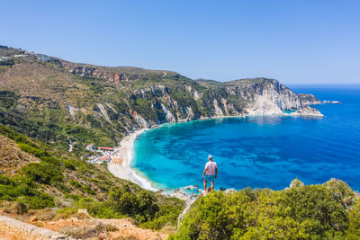 Rear view of man looking at sea against sky