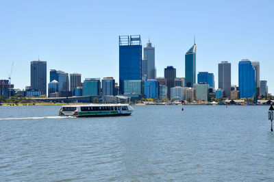 Boats sailing in river with city in background