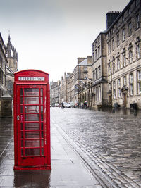 Telephone booth on wet sidewalk amidst buildings in city