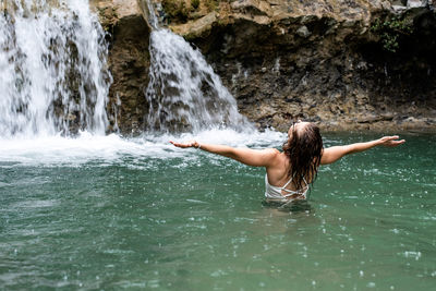 Tropical nature and vacation. woman swimming in the mountain river with a waterfall