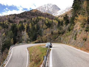 Vehicles on road by mountain against sky