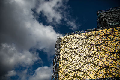 Low angle view of modern building against cloudy sky