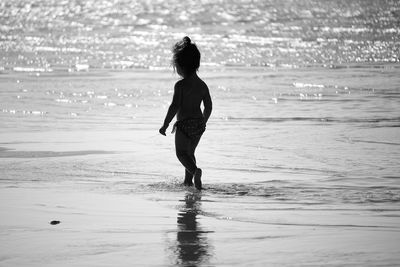 Rear view of young woman standing at beach