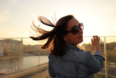 Portrait of woman wearing sunglasses while standing against river