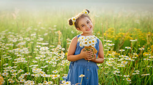 Pretty smiling little girl with a bouquet of daisies , stands in a field with daisies