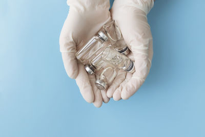 Close-up of hand holding blue over white background