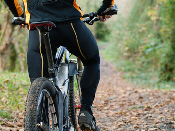 Low section of man riding bicycle at forest