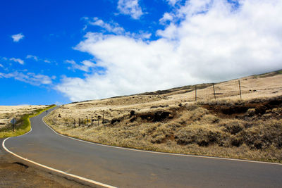 Empty road amidst land against sky