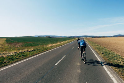 Rear view of man riding bicycle on road