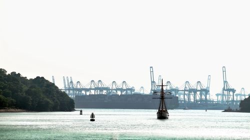 Cranes at harbor against clear sky