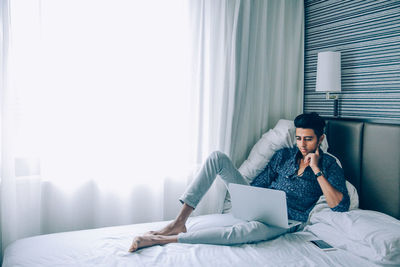 Woman using mobile phone while sitting on bed